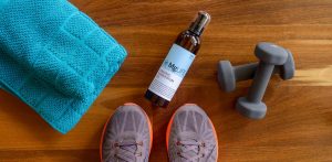 MgLife bottle with towel, free weights and gym shoes.